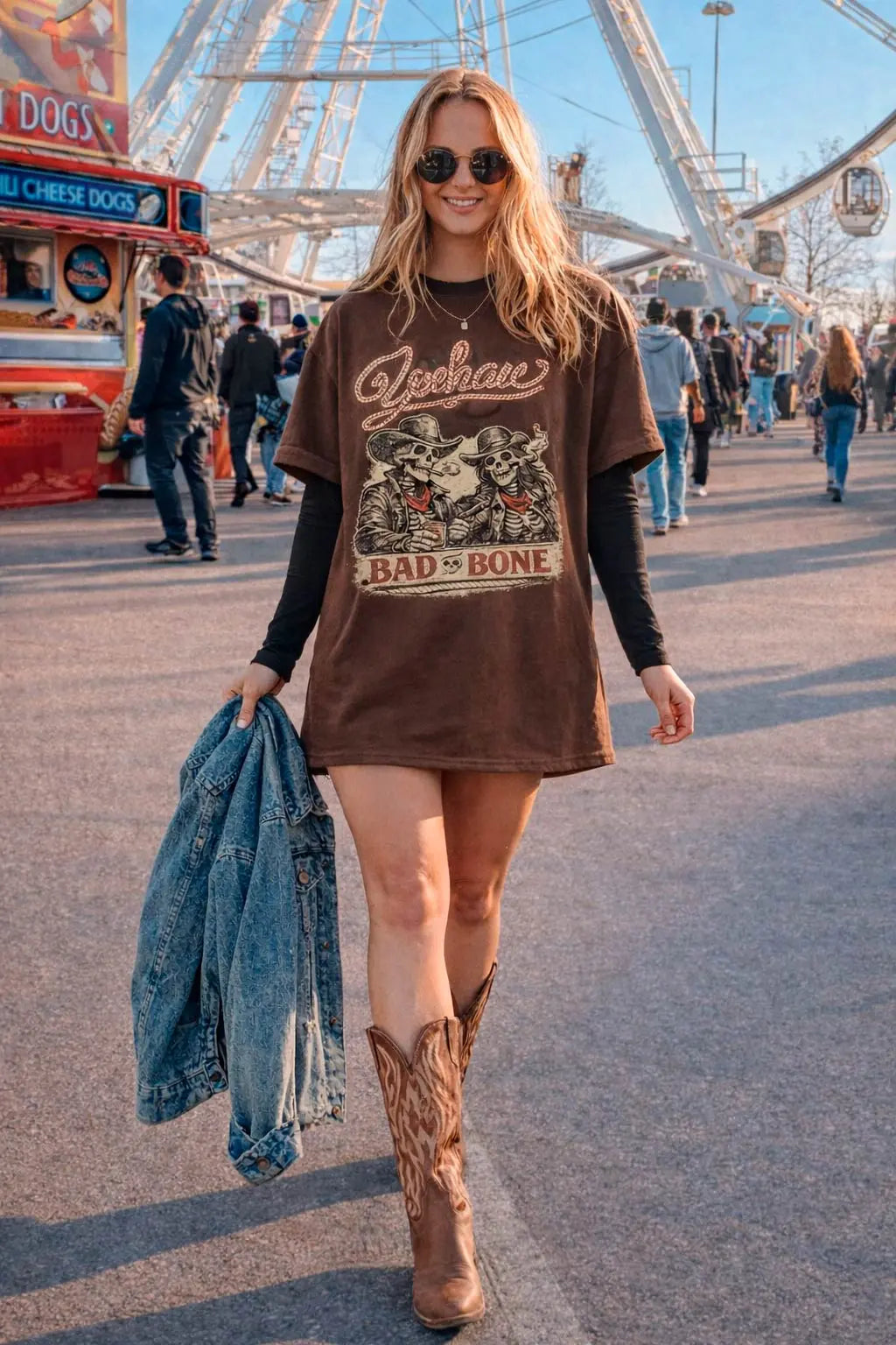 Woman wearing oversized vintage cowgirl graphic tee in brown with cowboy boots and denim jacket at a festival — Comfort Colors western t-shirt for women
