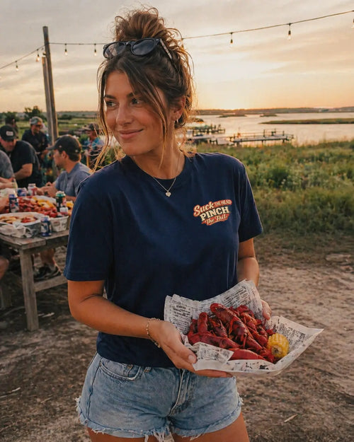Woman wearing Let The Good Times Boil crawfish graphic tee in navy at outdoor crawfish boil — crawfish boil shirt for women