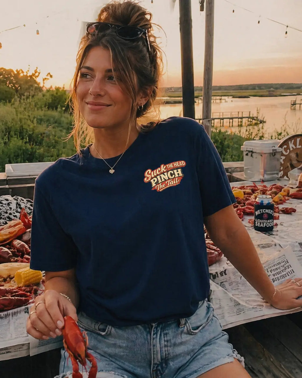 Woman holding crawfish wearing Let The Good Times Boil graphic tee — perfect crawfish boil outfit shirt for women