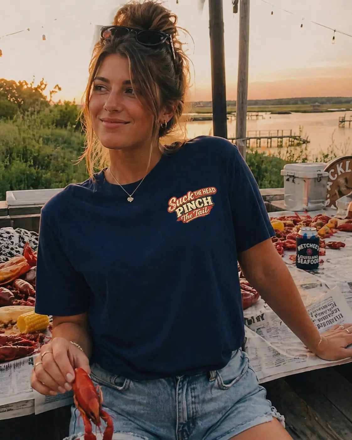 Woman holding crawfish wearing Let The Good Times Boil graphic tee — perfect crawfish boil outfit shirt for women