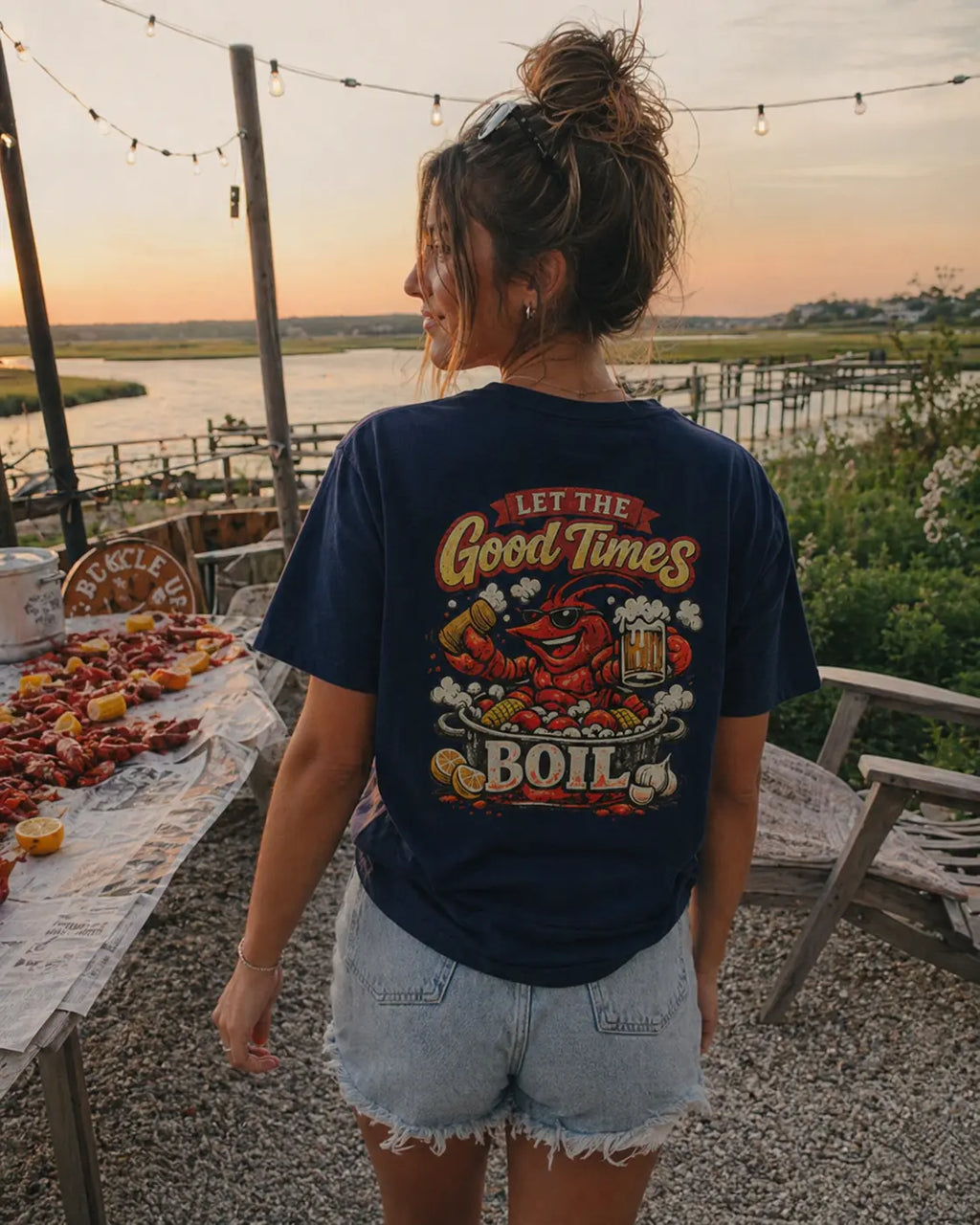 Let The Good Times Boil crawfish tee for women in navy — garment-dyed graphic shirt at sunset seafood boil