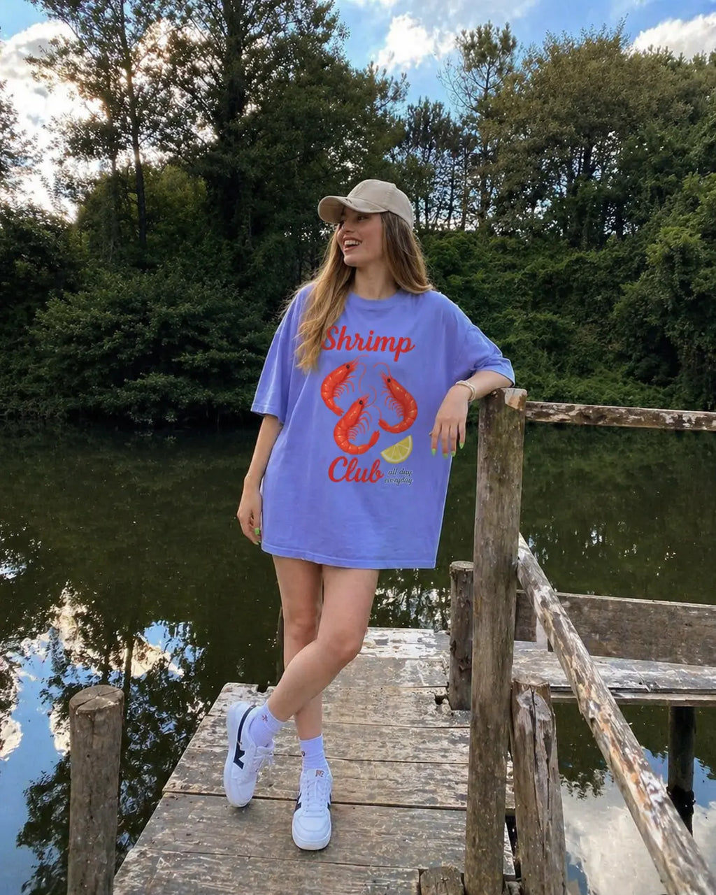 Woman wearing Shrimp Club seafood graphic tee in lavender sitting outdoors — oversized Comfort Colors tee for women