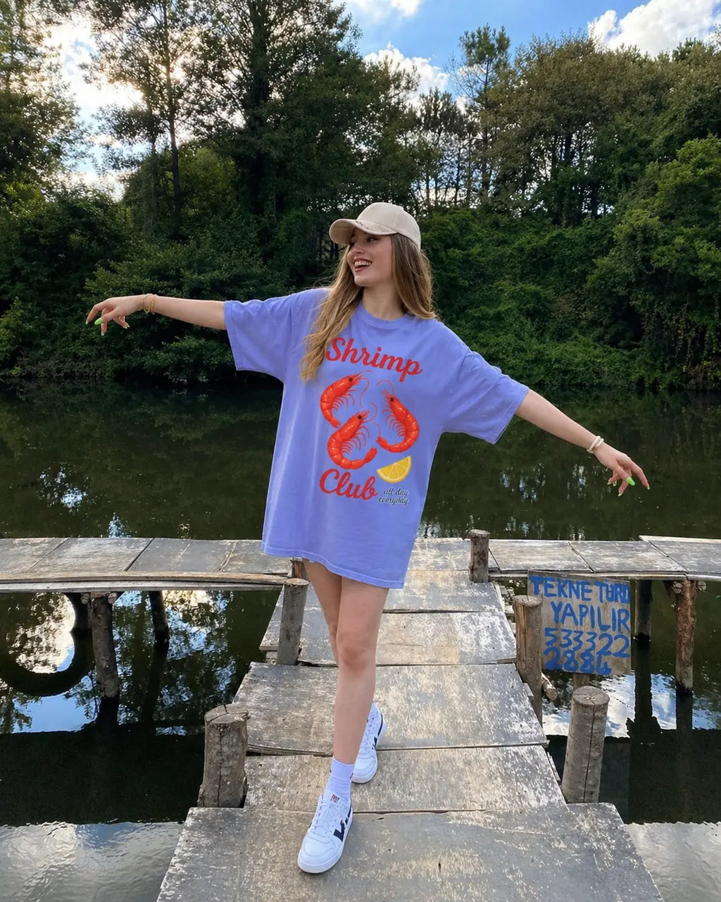 Woman wearing oversized Shrimp Club tee in lavender outdoors — seafood boil graphic t-shirt for women