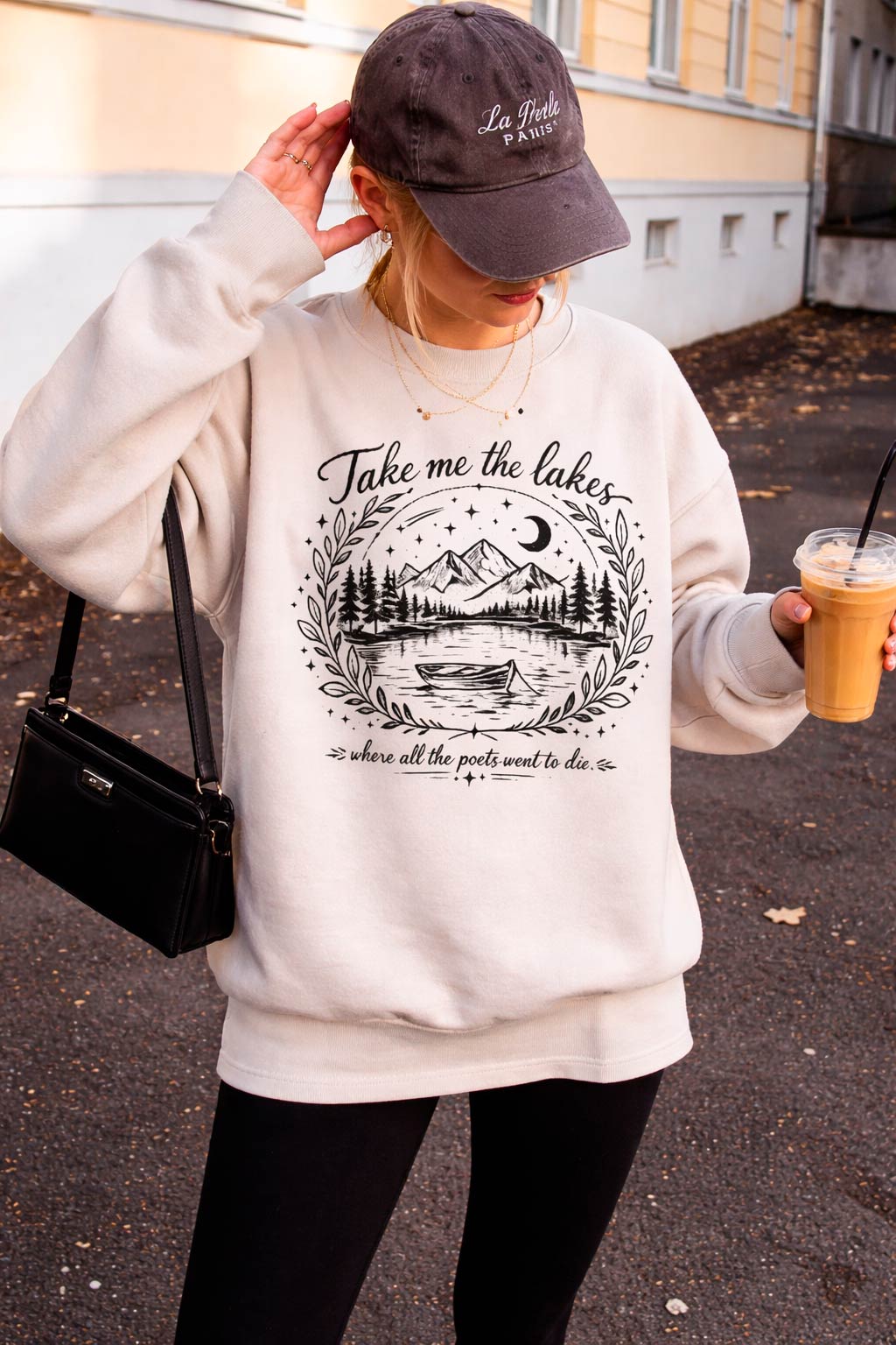 Woman walking around a street wearing The Lakes crewneck vintage graphic sweatshirt outdoors at golden hour