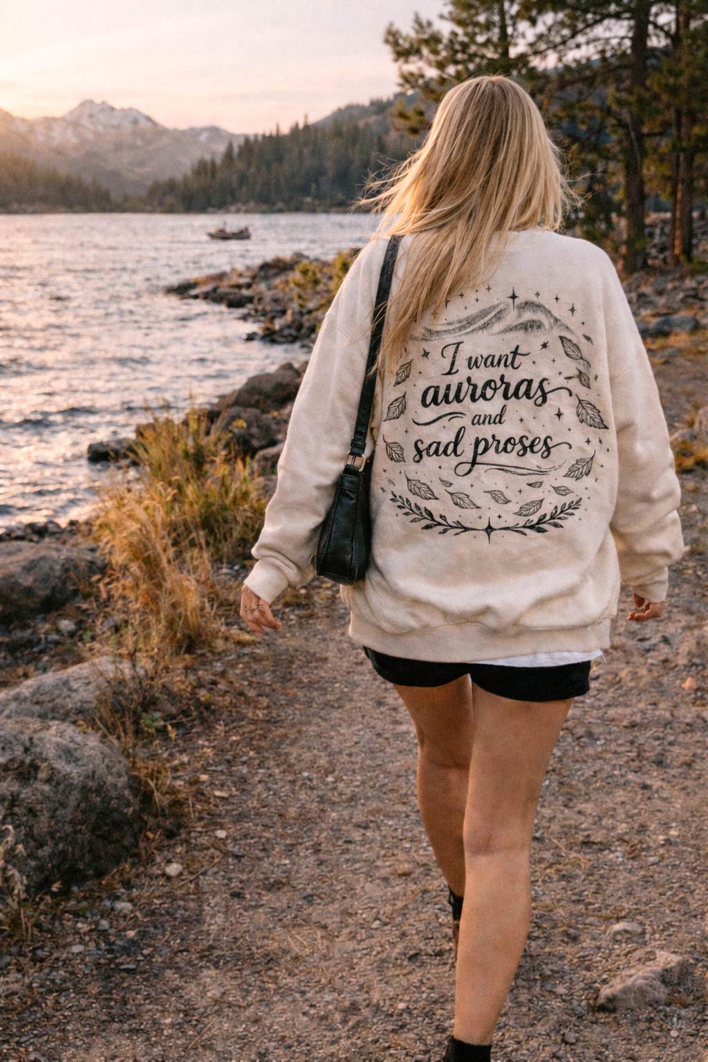 Aesthetic mockup of The Lakes crewneck sweatshirt worn by woman walking around a lake with mountains in background