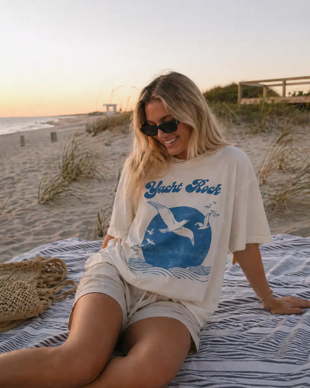 Woman seated on beach wearing Yacht Rock vintage ocean graphic tee — relaxed fit coastal t-shirt S-4XL